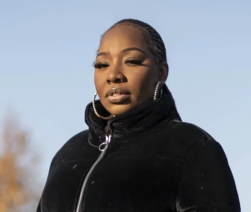 A woman standing outside in a park. she looks thoughtful