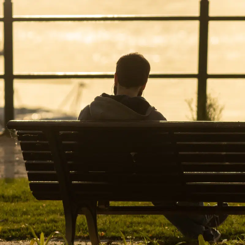 A man sits on a bench on his own.