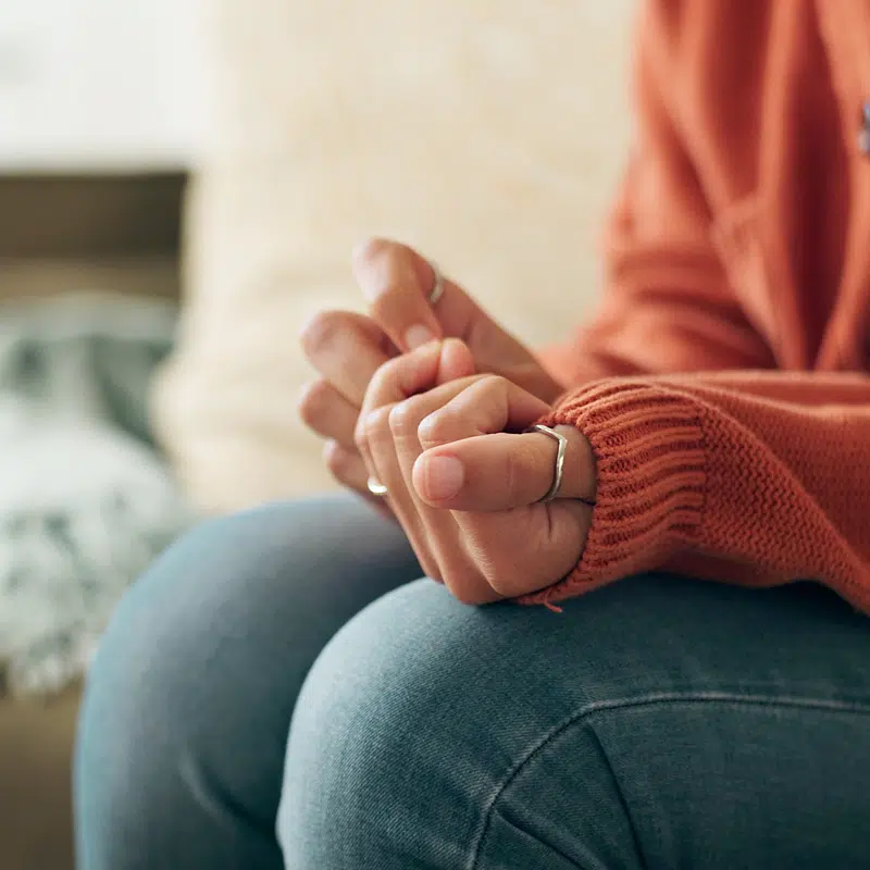 Hands clasped on a lap